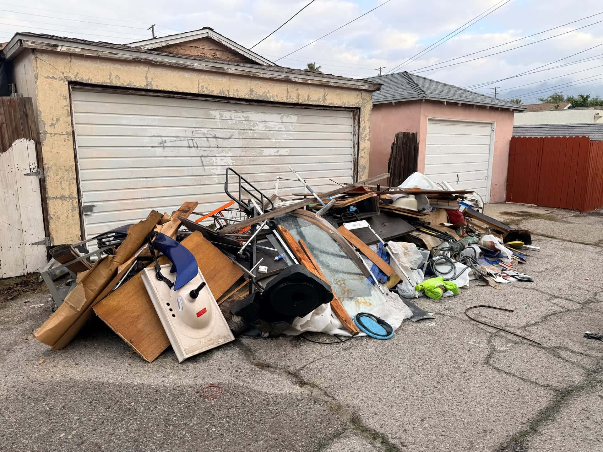 Before: a pile of broken furniture, boards and household junk outside an alley garage