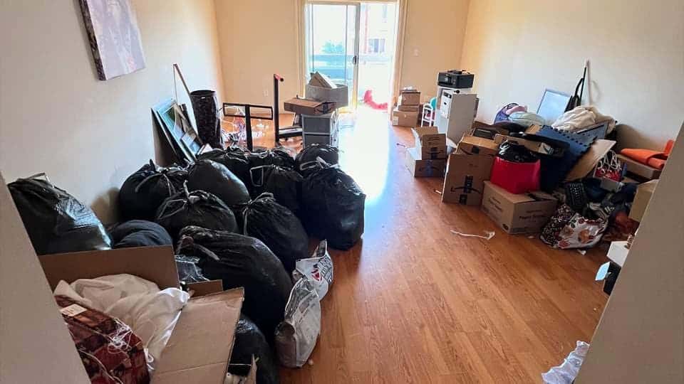 An apartment bedroom filled with black trash bags and boxes before a cleanout
