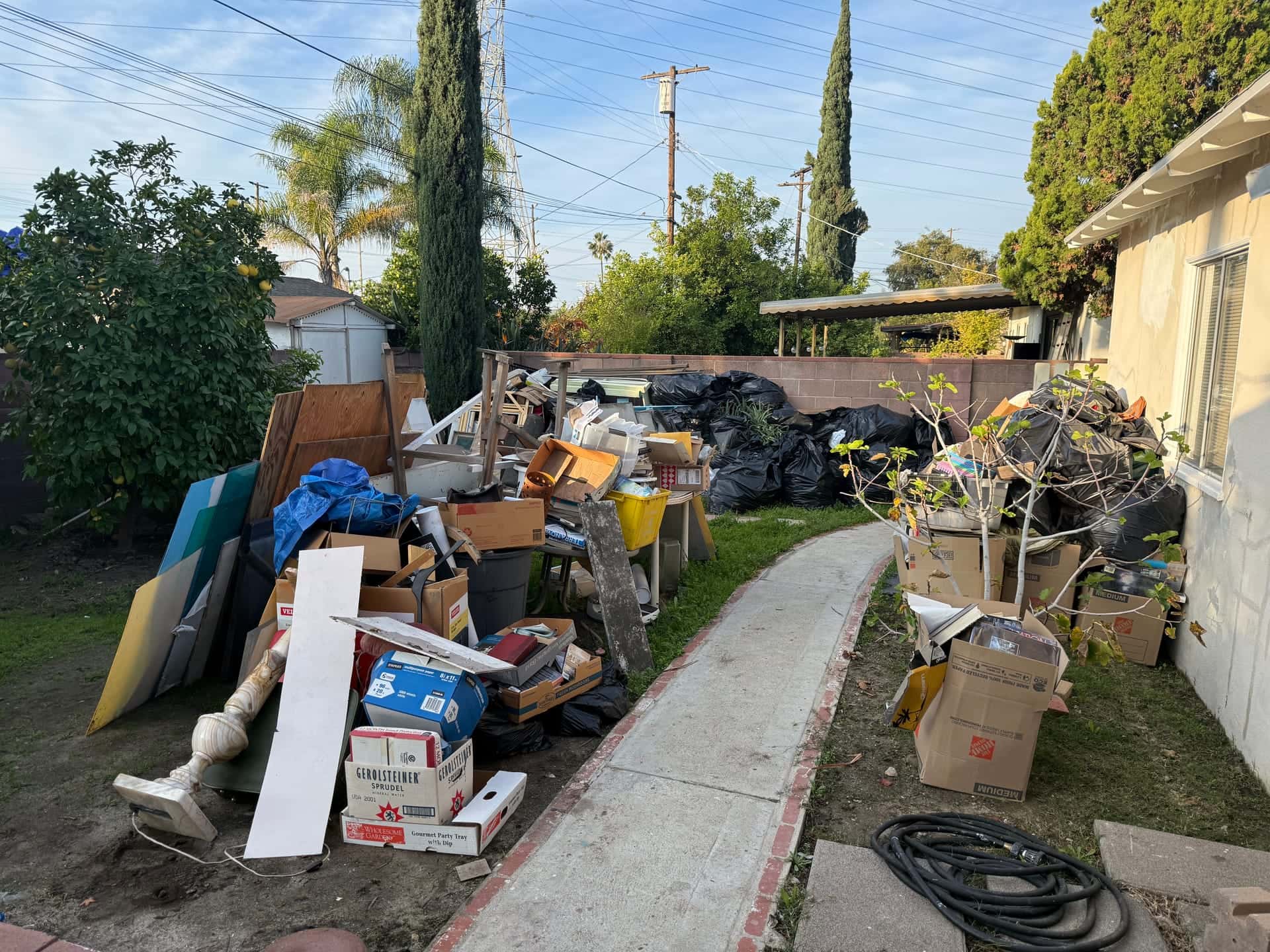 Before: boxes, boards, bags and furniture piled along a backyard path