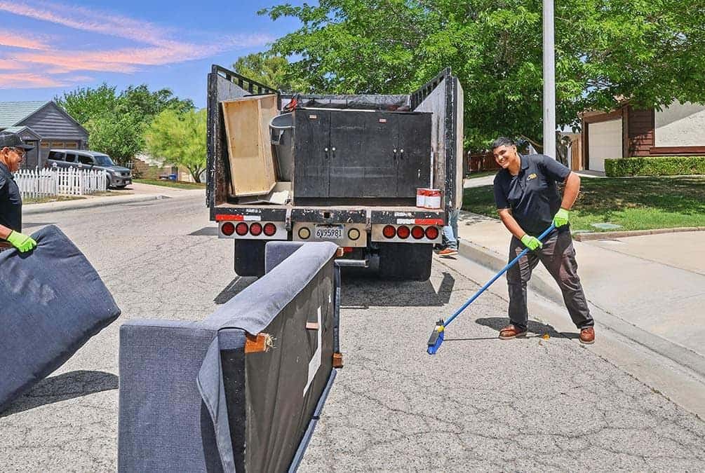 A Legacy crew member sweeping the curb behind the loaded truck