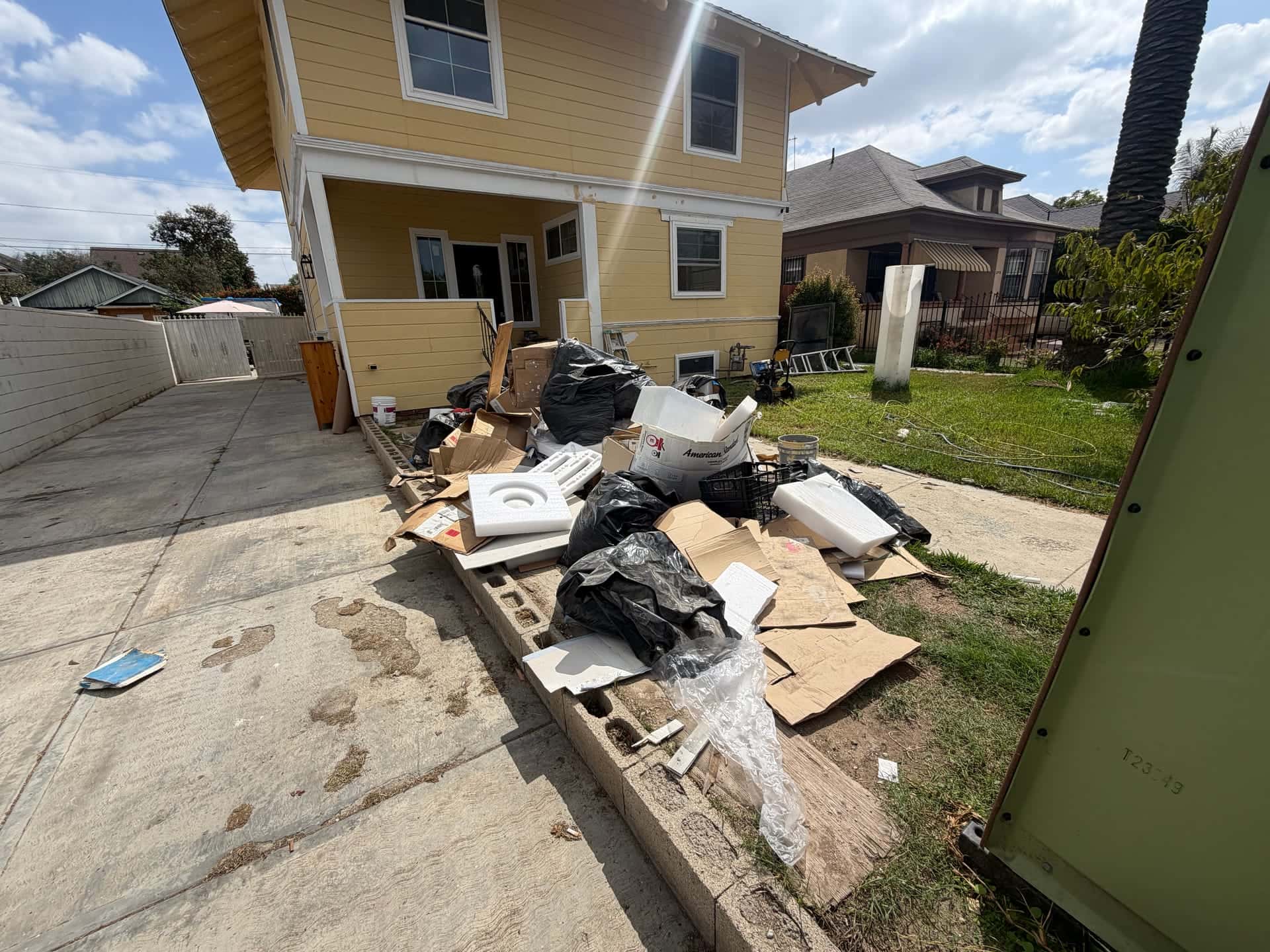 Before: bags, boxes and broken furniture piled along the front walk of a two-story house