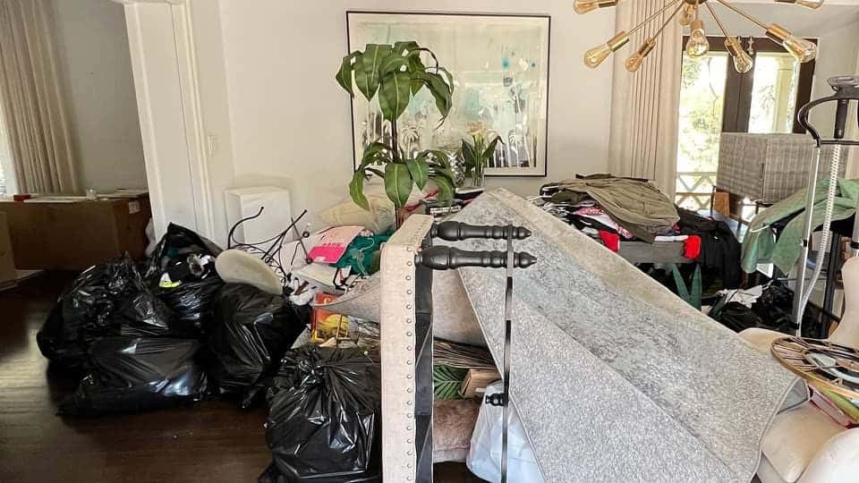 A living room mid-cleanout with bags, a mattress and furniture waiting to go