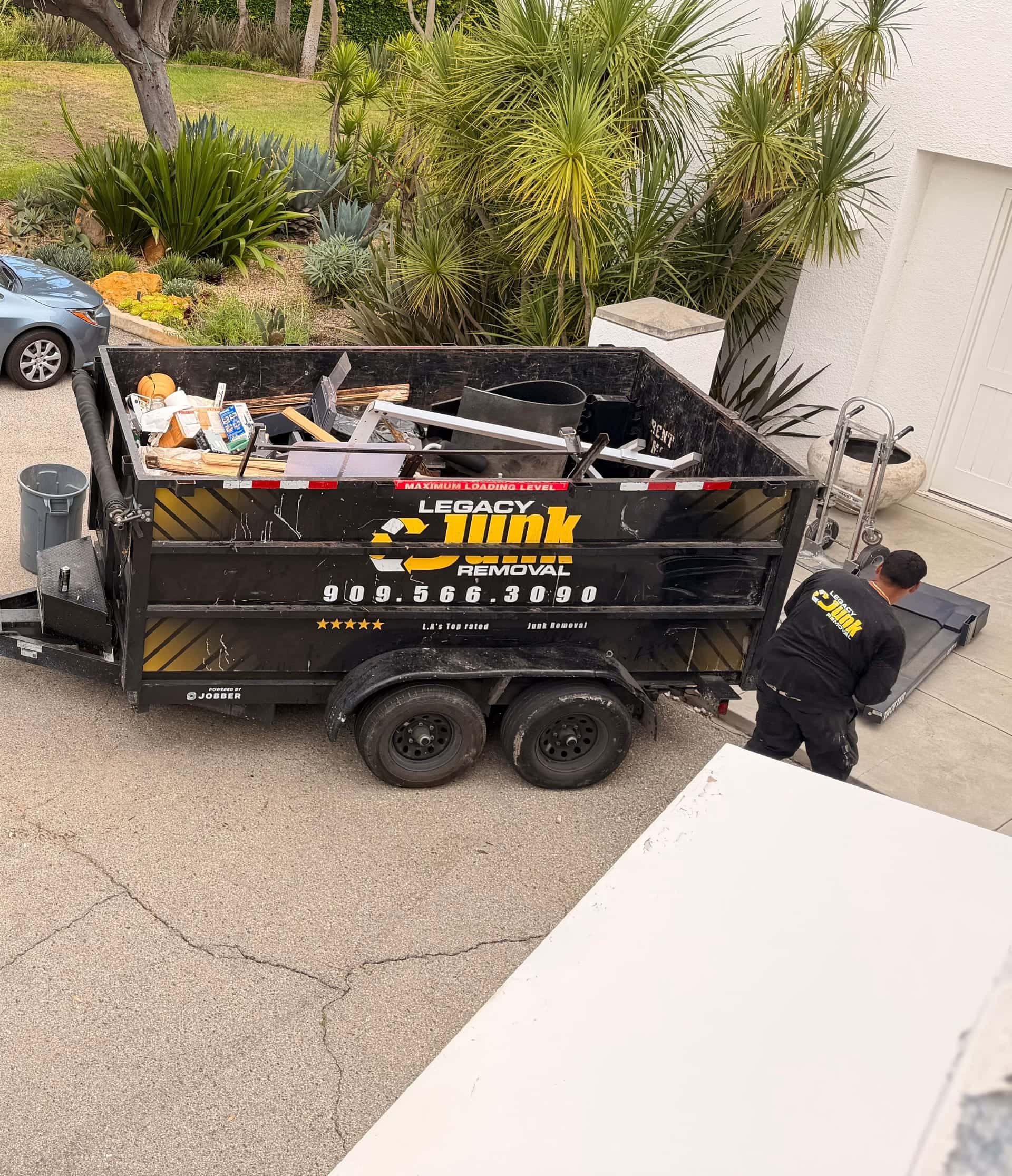 Looking down on a loaded Legacy trailer in a driveway while a crew member wheels a dolly up to it